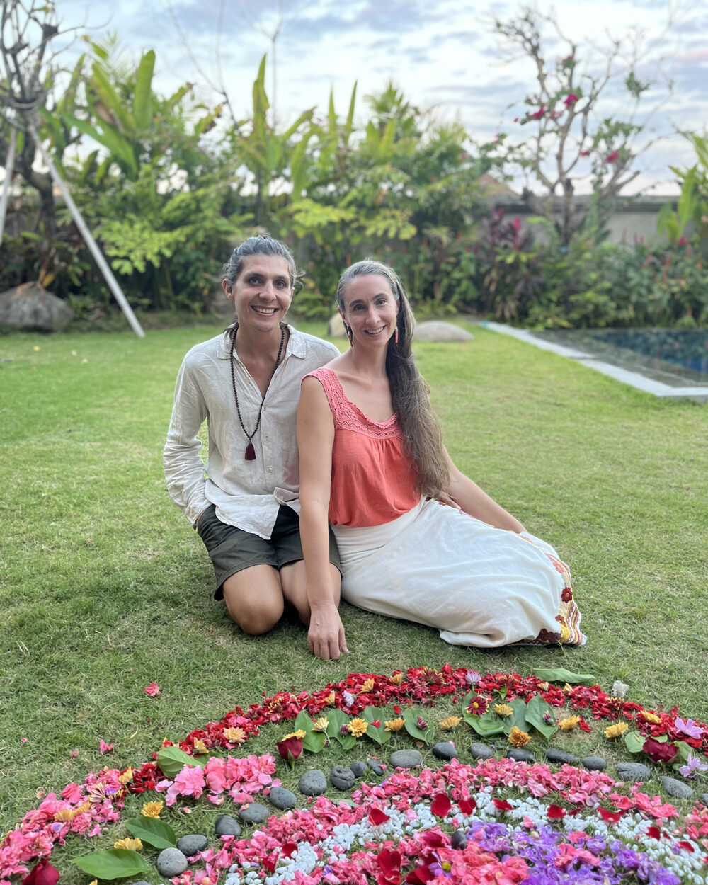 Adam and Andréanne sitting together at a flower mandala in their lush garden in Bali
