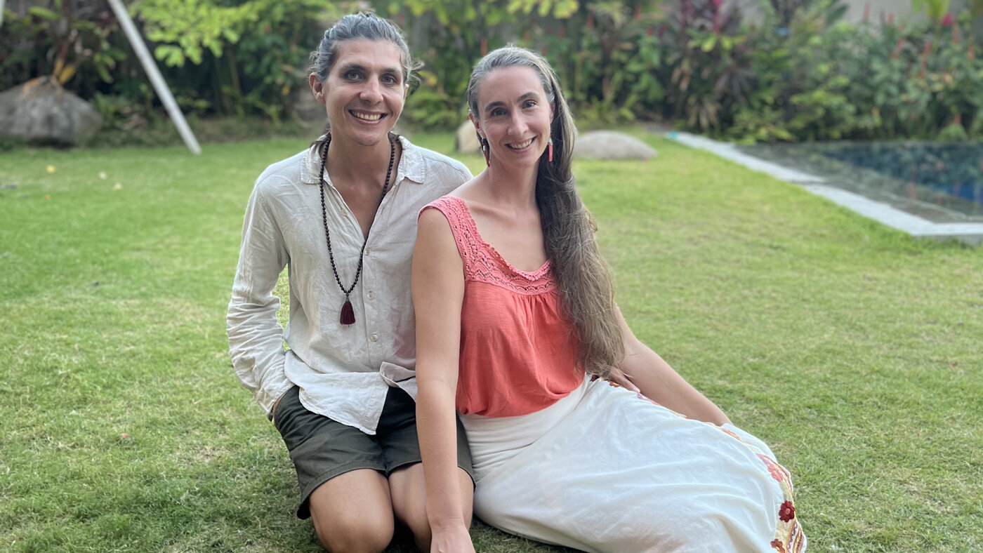 Adam and Andréanne sitting together on the grass in their garden, couples programs