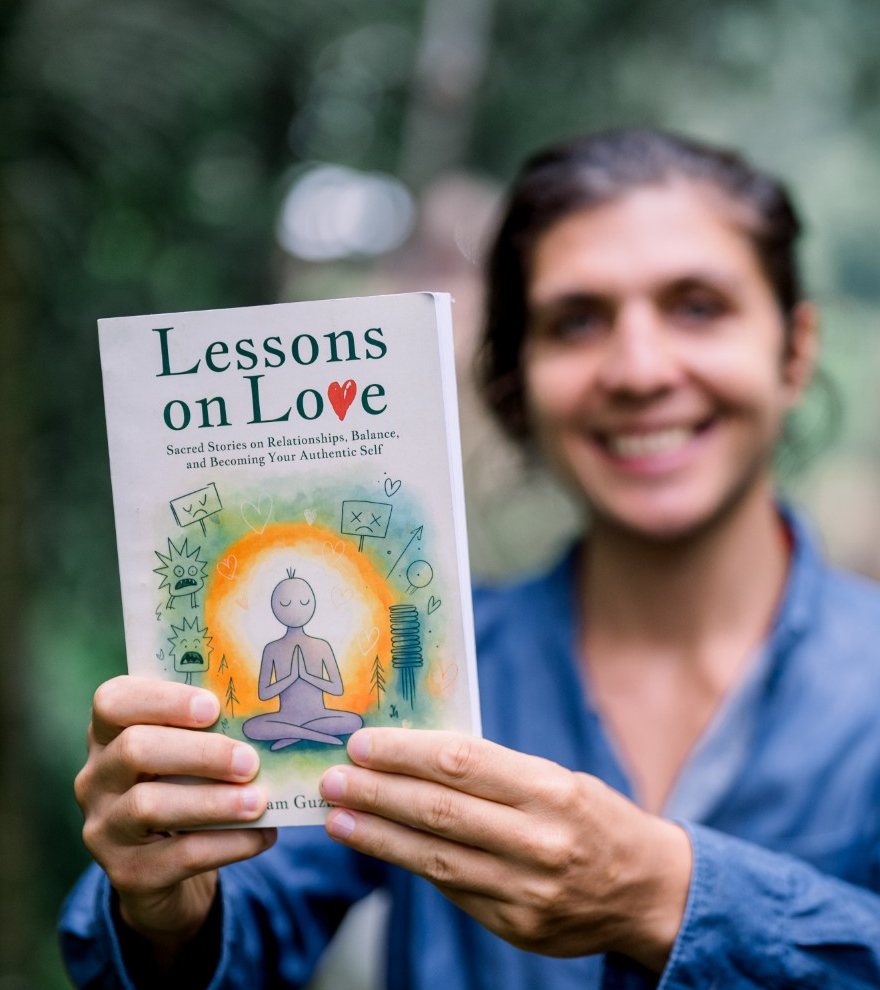 Adam Guzman-Poole smiling and holding out his book, Lessons on Love