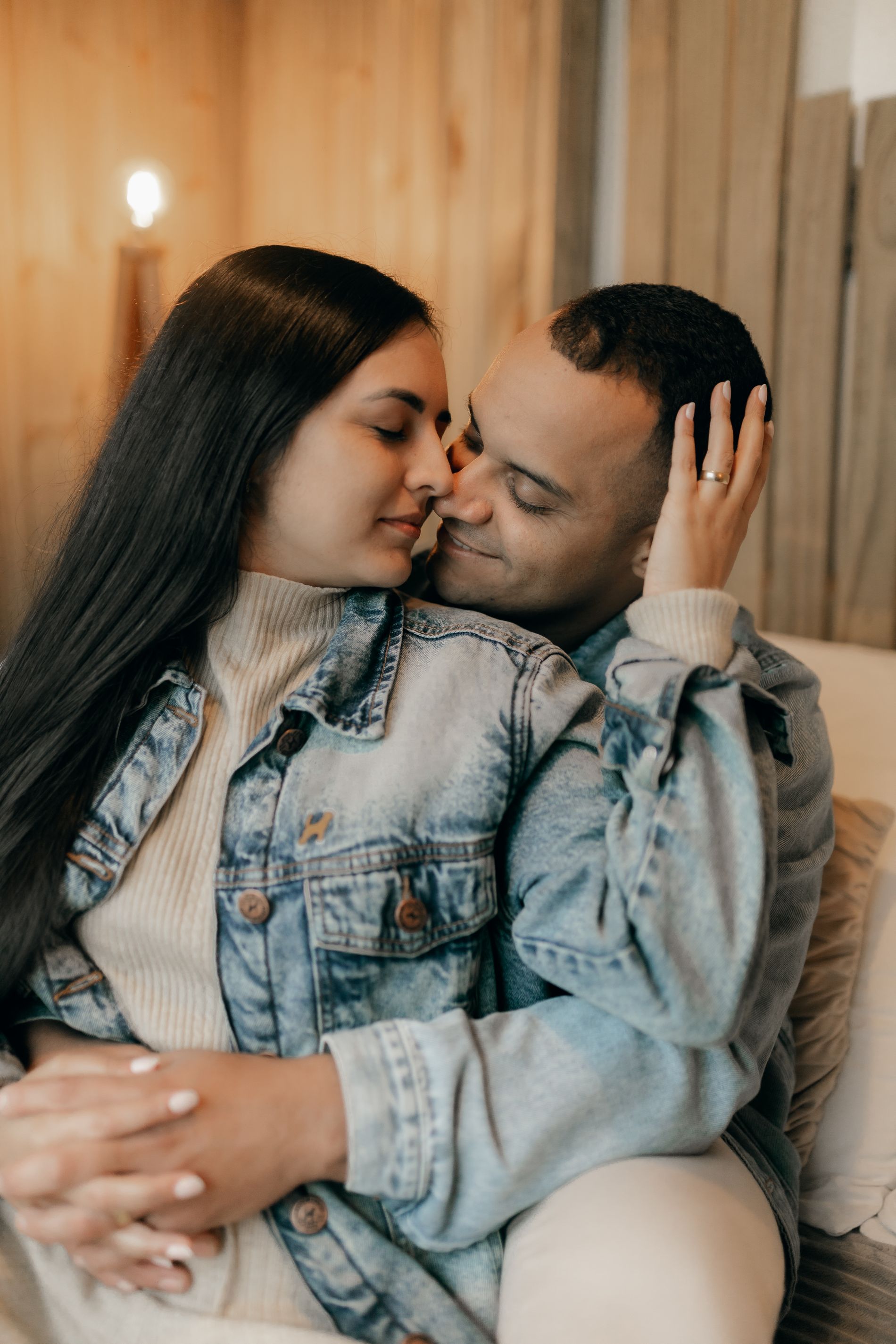 A couple close together at home in warm light, her hand resting on his face