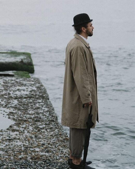 A man standing alone on the same grey pier, facing the other way