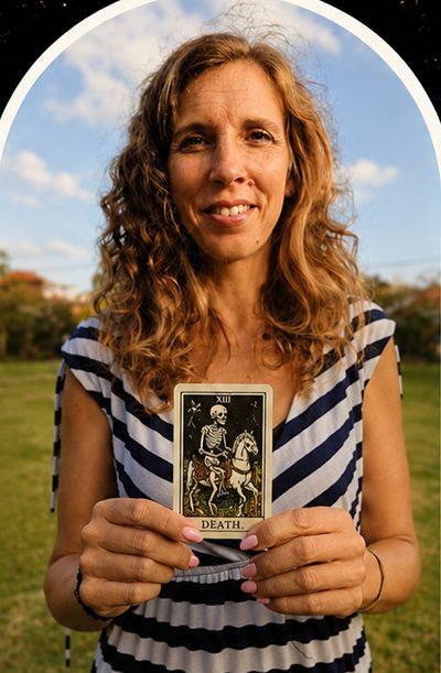 A client smiling in a sunny field, holding the Death card